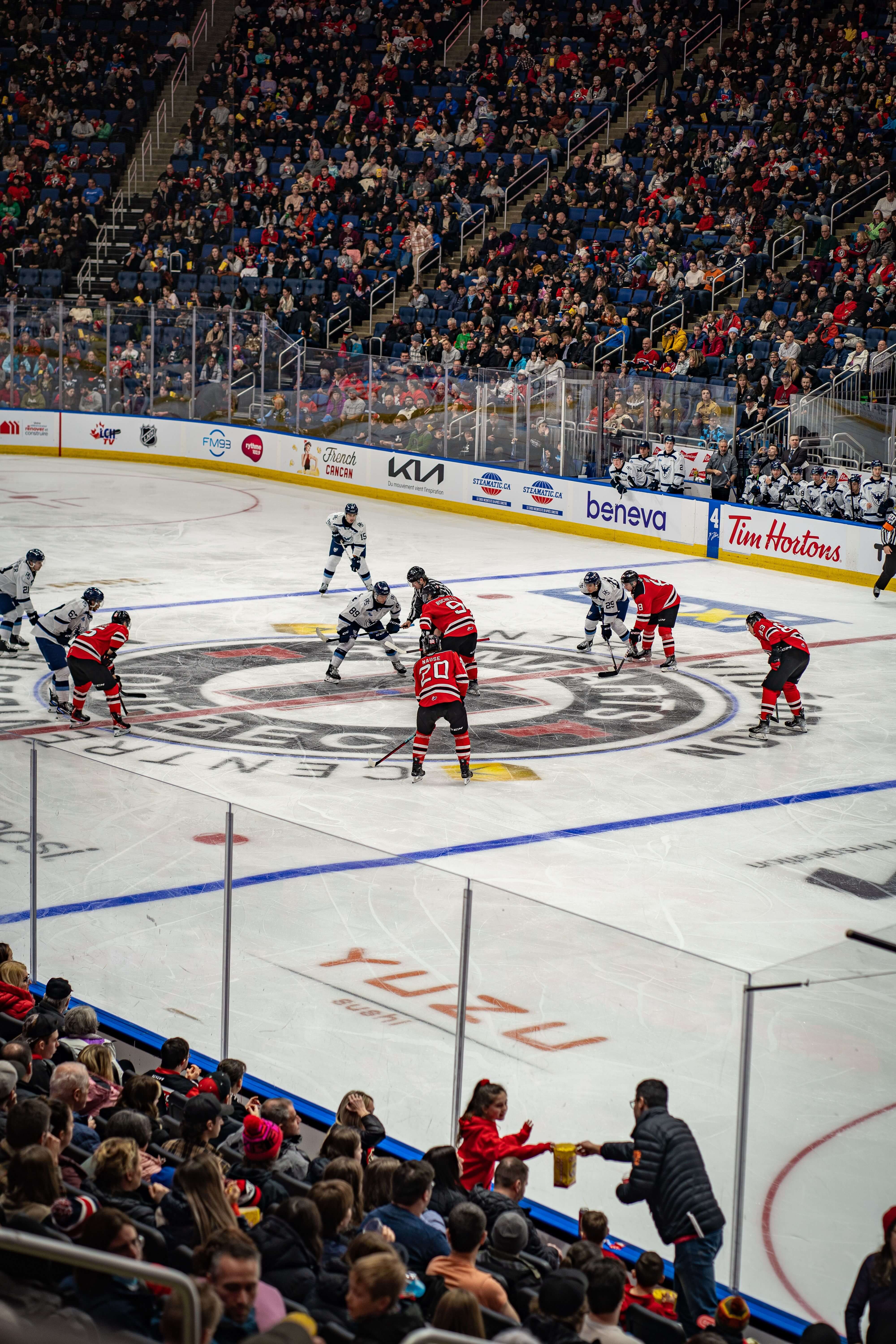 Hockey players on ice surrounded by fans in a packed arena