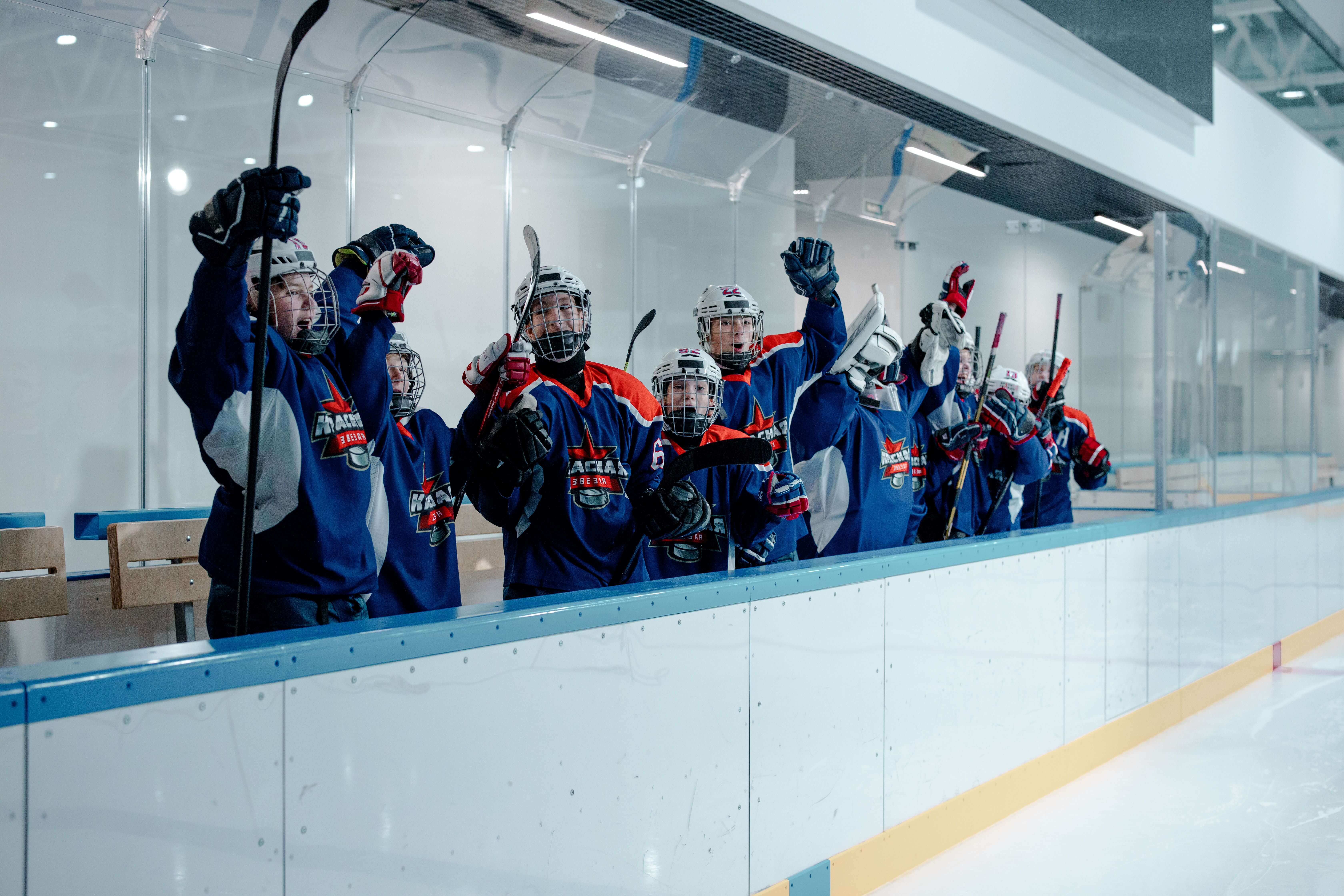 Hockey team cheering together in colorful jerseys inside an ice arena