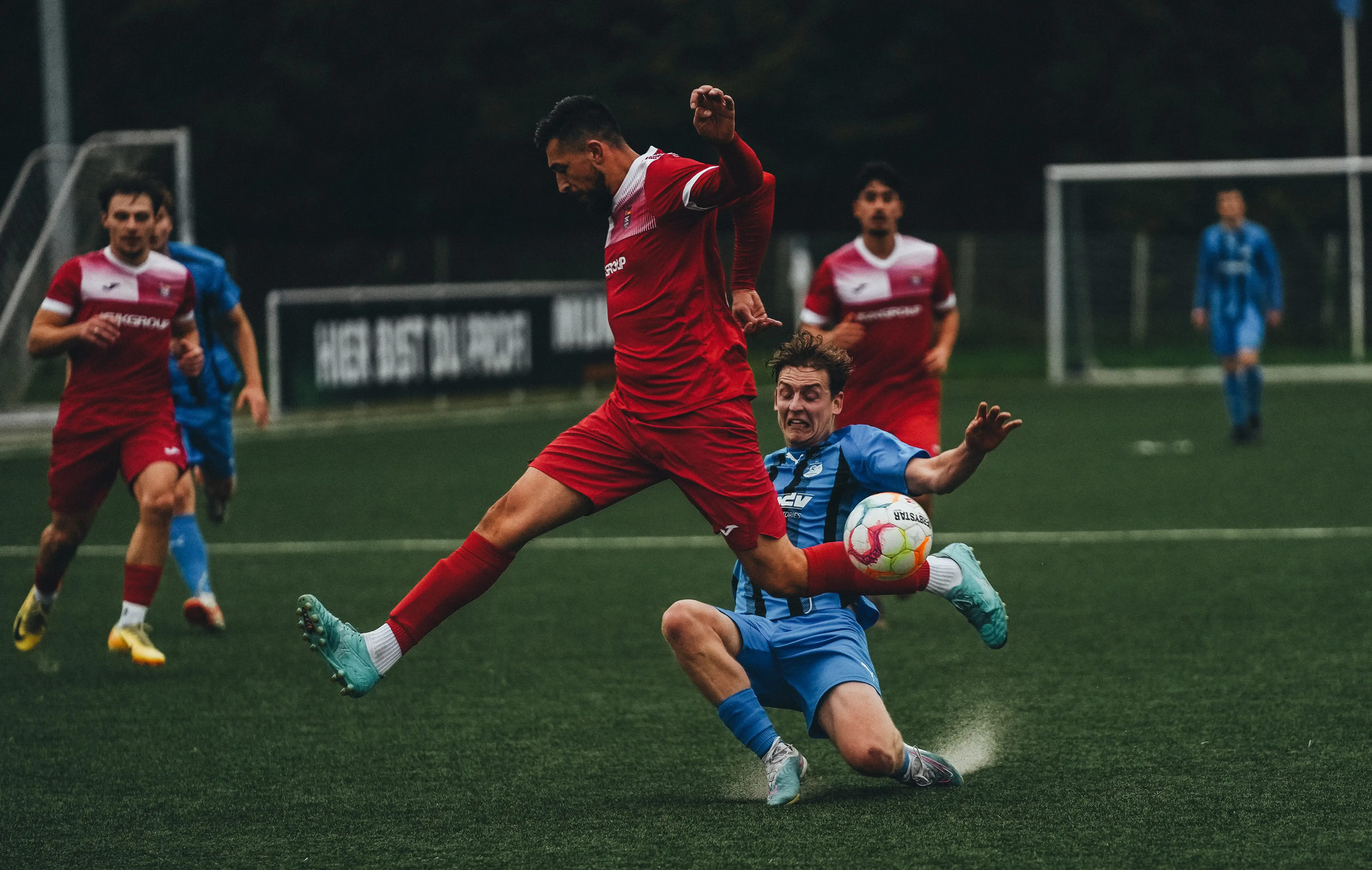 Several soccer players in game action on a wet grass field