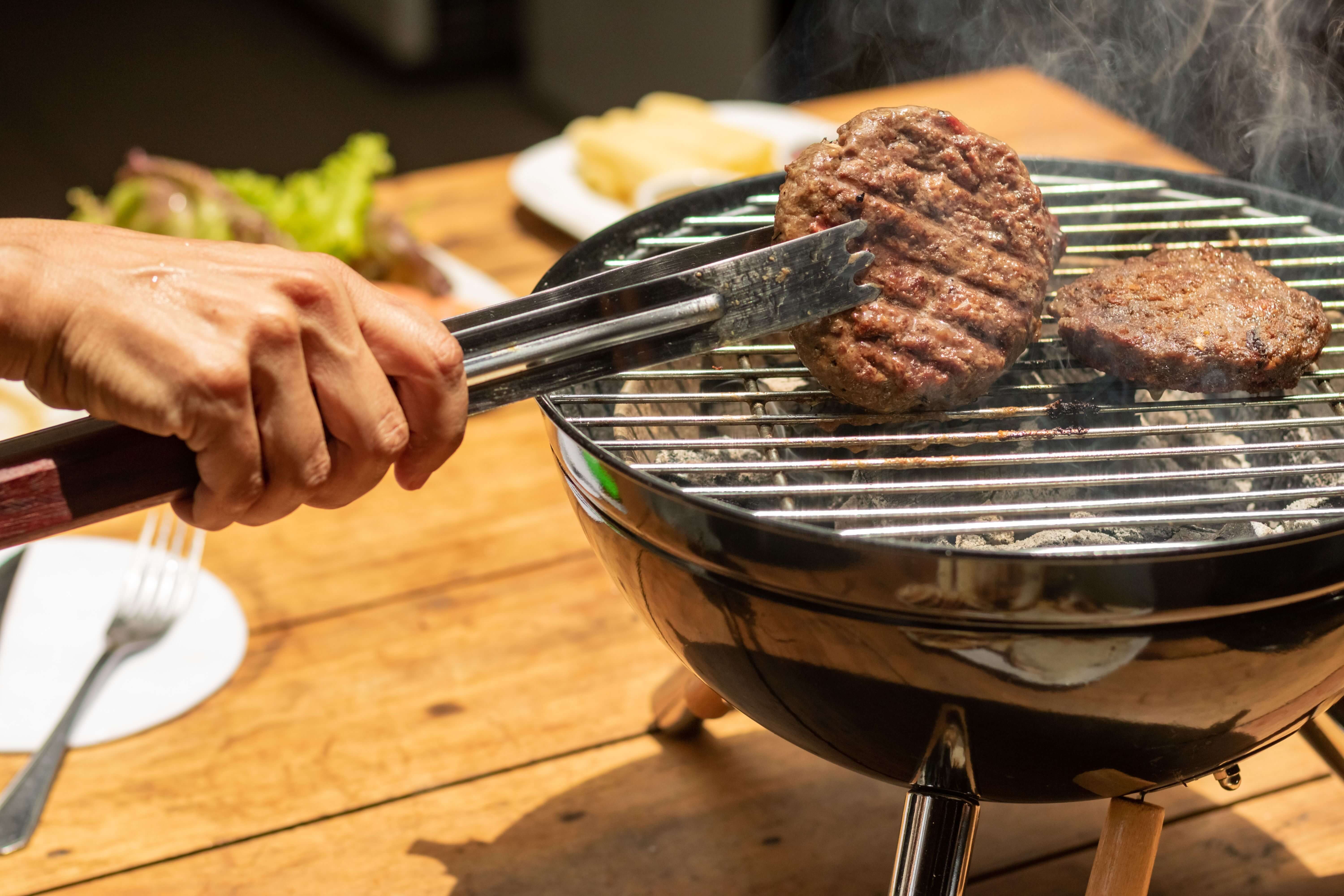 person grilling burgers on portable grill